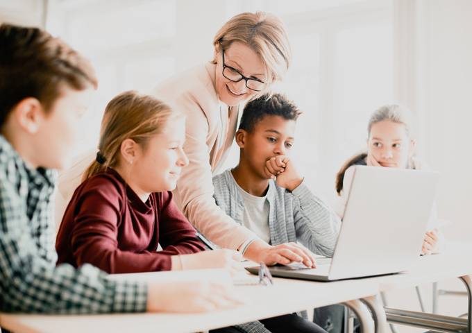 Teacher helps her students use the laptop